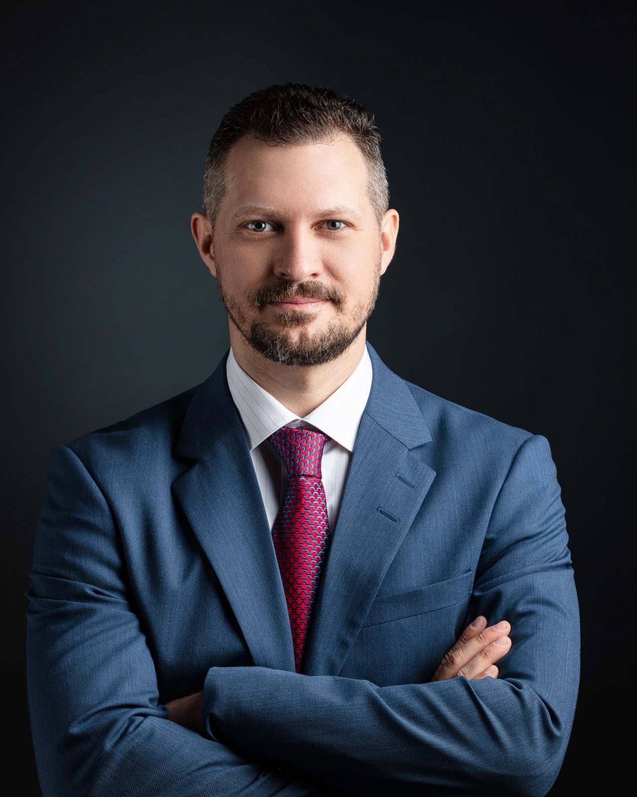 Sascha Getzinger, Principal von Getzinger & Partners, im dunklen Anzug vor anthrazitfarbenem Studiohintergrund